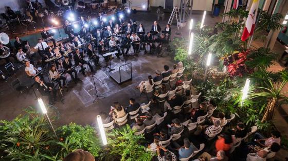 Banda de Conciertos de Heredia tocando en el Centro Cultural Omar Dengo. Público sentado y rodeado de luces escuchando a la Banda.