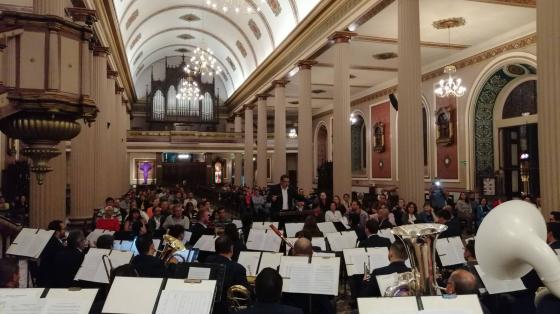 Músicos de la Banda de Conciertos de San José tocando en una iglesia con mucho público asistente