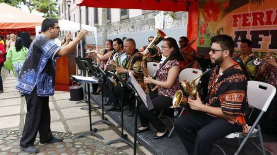 Músicos de la Banda de Conciertos de Limón tocando en una plaza. Los músicos visten camisas con diseños y colores de la cultura afrodescendiente. 