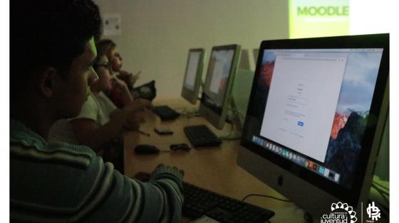 Jóvenes frente a pantallas de computadoras recibiendo lecciones