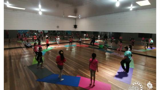Niños en una clase de yoga, todos de pie sobre una manta de yoga