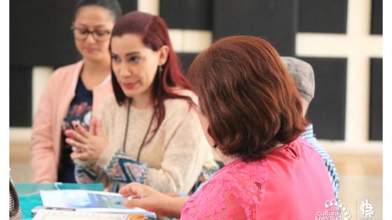 Taller virtual: Indicadores básicos de productividad Tres personas alrededor de una mientras explica un tema