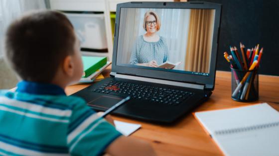 Educación en línea Niño frente a computadora mientras su profesora da clases