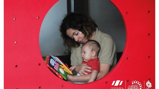 Una mamá enseñándole un libro y leyéndole a un bebé