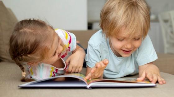 Un niño y una niña leyendo en el piso