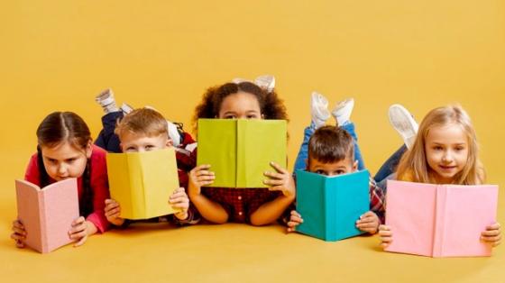 Grupo de niños cubriéndose la cara con libros