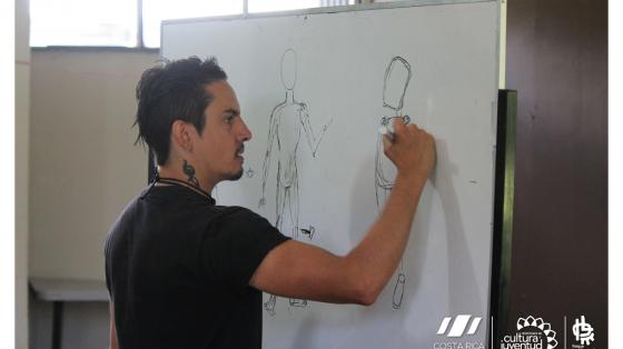 Profesor dando clases de dibujo mientras dibuja en una pizarra