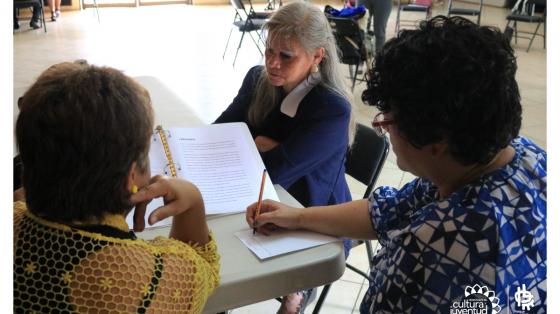 Taller Proceso de oferta y adjudicación en SICOP Tres personas en una mesa aprendiendo a aplicar un nuevo proceso