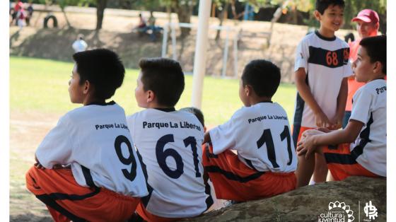 Grupo de niños prestando atención en un clase de fútbol