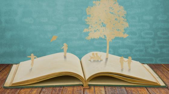 Libro abierto con siluetas de papel de niños y niñas en la naturaleza. 