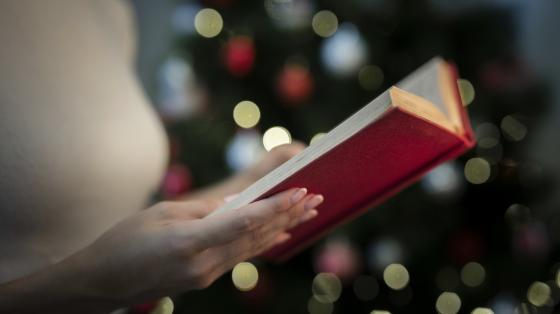 Mujer leyendo un libro en un fondo navideño. 
