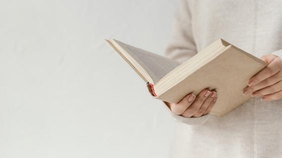 Mujer sosteniendo un libro abierto.