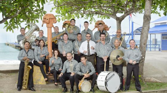 Músicos de la Banda de Puntarenas bajo uno árboles