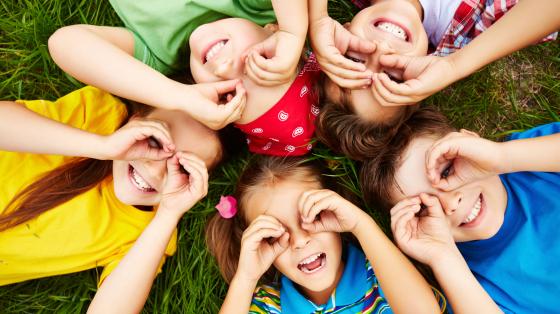 Niños y niñas jugando en zona verde.