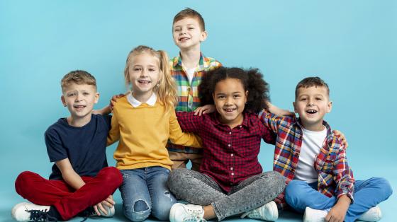 Fotografía con fondo celeste. Se presentan tres niños y dos niñas. 