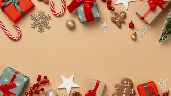 Fondo amarillo. Elementos navideños como regalos, ornamentos, galletas de navidad y melcochas.