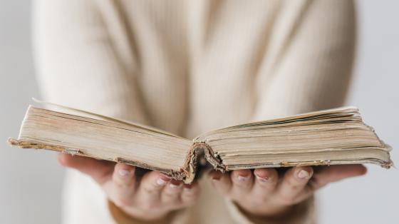 Persona sosteniendo un libro abierto. 