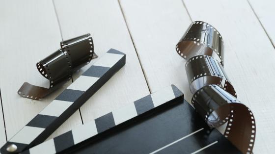 Cine al aire libre Sobre una mesa de madera blanca, cinta cinematográfica y claqueta.