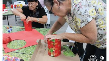 Dos señoras realizando adornos navideños con material reciclado.