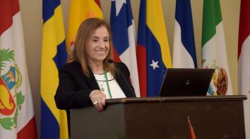 Fotografía de Teresita Aguilar y en el fondo un grupo de banderas