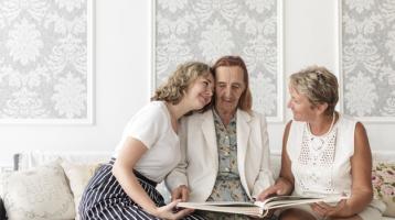 Nieta abrazando a su abuela y mirando fotografías en un álbum familiar