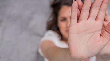 Mujer colocando la mano abierta adelante, en señal de protegerse