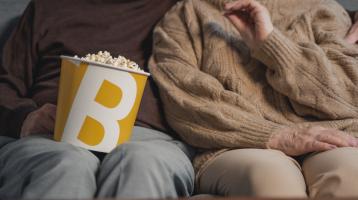 Pareja de adultos mayores compartiendo palomitas de maíz.