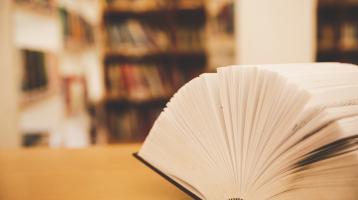 Libro abierto sobre una mesa de madera. 