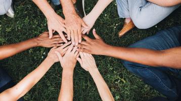 Grupo de personas uniendo sus manos en el parque.