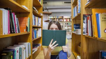 Mujer sosteniendo un libro abierto en la biblioteca.