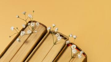 Fotografía con fondo amarillo. Se presentan tres libros y entre sus páginas flores.