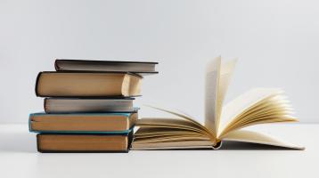 Fotografía de una torre de libros y un libro abierto. 