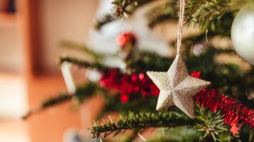 Fotografía enfocando un ornamento de estrella en un árbol de navidad.