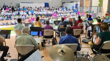 Foto de los músicos tocando frente a niñas y niños de una escuela