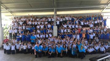 Foto de la Banda con niñas y niños al fondo disfrutando el Concierto Didáctico