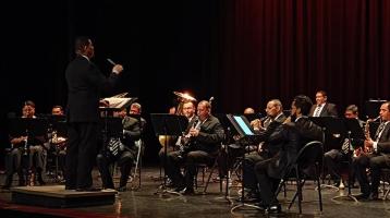 Foto de los músicos de la Banda vestidos elegantemente en un teatro