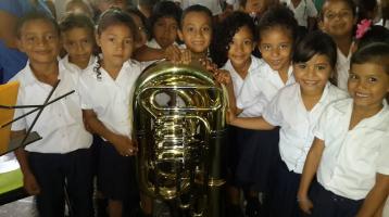 Niños y niñas sonriendo y rodeando a una Tuba